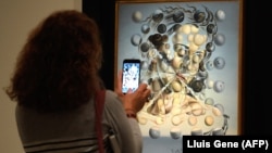 A visitor takes a picture with his smatphone at the painting "Gala lacidia,1952" by artist Salvador Dali